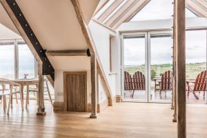 a room with a table and chairs and windows at Seaview Penthouse 2 in Alnmouth