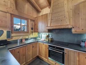 une cuisine avec des armoires en bois et un four à plaques de cuisson dans l'établissement Chalet familial à Courchevel, proche centre et pistes, avec sauna et jacuzzi - FR-1-562-54, à Courchevel 6 autres photos