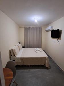 a small room with a bed and a television at Hospedaria Casa da Lia in Mucugê