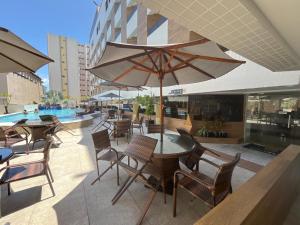 a patio with tables and chairs and an umbrella at Gold Flat Cabo Branco in João Pessoa