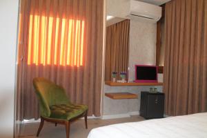 a bedroom with a bed and a green chair and a television at Lila Butik Hotel Dikili in Dikili