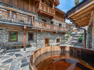 an outdoor patio with a hot tub in front of a building at Chalet de prestige au cœur de Saint Martin de Belleville, à quelques pas des pistes - FR-1-570-38 in Saint-Martin-de-Belleville