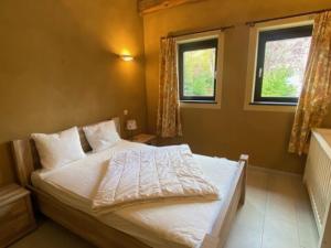 a bedroom with a bed with white sheets and two windows at Maboge 20C in La Roche-en-Ardenne +2 photos