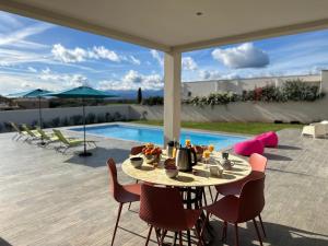 a patio with a table and chairs and a pool at Spacieuse villa standing de 220m2 in Aléria