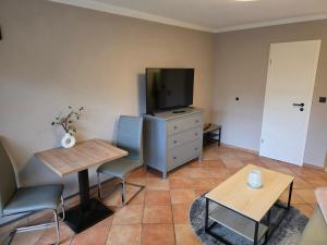 Una sala de estar con televisión, mesa y sillas. en Appartment Zweierlei, en Zingst
