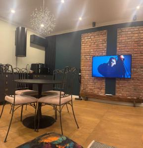 ein Esszimmer mit einem Tisch und einem Fernseher an einer Ziegelwand in der Unterkunft SSN Apartment in Turda