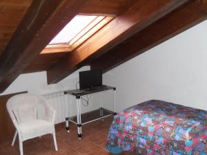- une chambre avec un lit, une télévision et une chaise dans l'établissement Agriturismo Le Giare, à Gênes