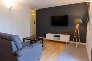 een woonkamer met een bank en een tv aan de muur bij Évasion et Confort Aubagne in Aubagne