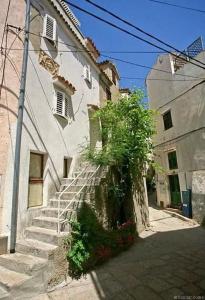 a white building with stairs and a tree next to it at Studio In Einem Traditionellen Steinhaus, In Baska in Baška