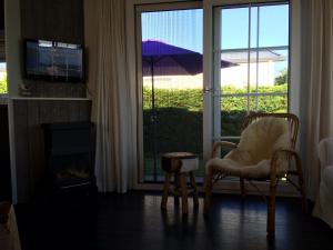 sala de estar con silla y puerta corredera de cristal en Chalet Zilt Ameland, en Hollum