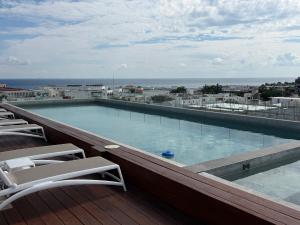 プラヤ・デル・カルメンにあるStudio de luxe Duna 206の椅子付きの建物の最上階にあるスイミングプール