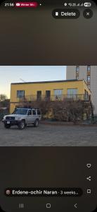 a car parked in front of a yellow building at Bee Happy Hostel & Gobi amazing tour in Dalandzadgad