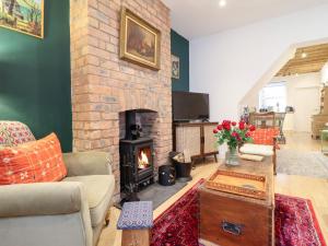 a living room with a brick fireplace and a couch at Derwen House in Llangollen