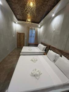 - une chambre avec 2 lits dotés de draps blancs et d'un lustre dans l'établissement Kawayan Hostel, à General Luna