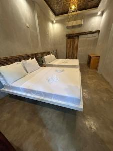 une chambre avec deux lits avec des draps blancs dans l'établissement Kawayan Hostel, à General Luna