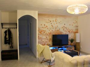 ein Wohnzimmer mit einem TV und Vögeln an der Wand in der Unterkunft Maison cosy - Logis Flo - à 15 min du Futuroscope in Beaumont