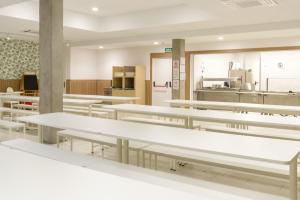 una cafetería con mesas blancas y una cocina en Hostal Welcome, en Madrid