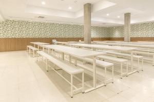 Un comedor con mesas blancas y bancos blancos. en Hostal Welcome, en Madrid