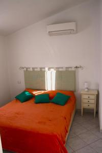 une chambre avec un lit avec des draps orange et des oreillers verts dans l'établissement La casa 3M L, à Santa Maria