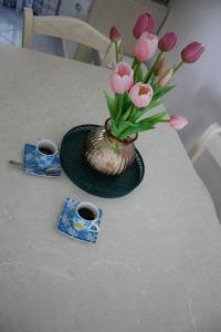 un vase avec des fleurs roses sur une table avec deux tasses dans l'établissement La casa 3M L, à Santa Maria