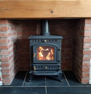 a wood stove in a brick fireplace at Copper Mine Cottage in Llandudno