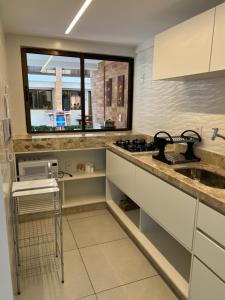 a kitchen with white cabinets and a sink and a window at Casa em condomínio na praia in Cabedelo