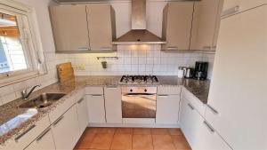 a white kitchen with a stove and a sink at Hello Zeeland - Oosterpark 14 in Oostkapelle