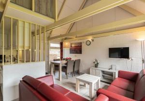 a living room with a red couch and a table at Bungalowpark Simpelveld - Alpha 97 in Simpelveld