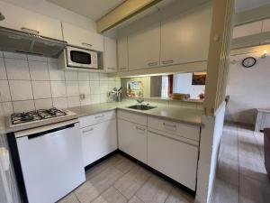 a kitchen with white cabinets and a sink and a stove at Bungalowpark Simpelveld - Alpha 97 in Simpelveld