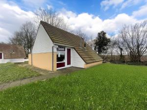a small house with a large grassy yard at Bungalowpark Simpelveld - Alpha 97 in Simpelveld