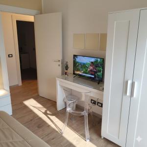 a living room with a tv and a table with a chair at Etna Charme Guest House in Belpasso