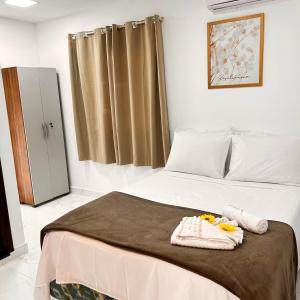a bedroom with a bed with towels on it at Residencial Angelina in Praia do Forte