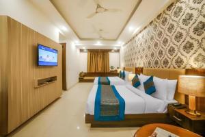 a hotel room with a bed and a flat screen tv at Hotel Almati Inn Near Delhi Airport - With Free Airport Pickup in New Delhi