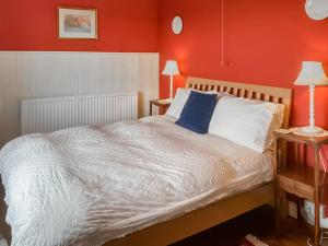 a bedroom with a white bed with red walls at Downhouse Cottage in Delabole +22 photos