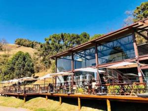 ein Gebäude mit Tischen und Sonnenschirmen an einem Fluss in der Unterkunft Casa SERRA DA BALANÇA - PÉROLA DA MANTIQUEIRA in Gonçalves