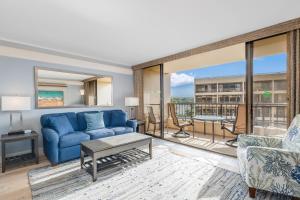 un salon avec un canapé bleu et une table dans l'établissement Sugar Beach Resort 505 condo, à Kihei