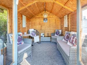 a porch with wicker chairs and a table at Hyfrydle Cottage in Pen-y-groes