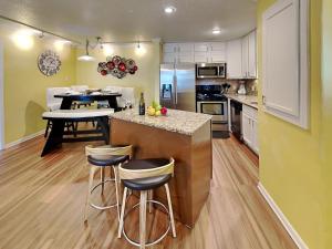 a kitchen with yellow walls and a island with bar stools at Seaside Delight in Mustang Beach