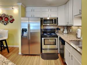 a kitchen with stainless steel appliances and white cabinets at Seaside Delight in Mustang Beach