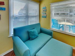 a blue couch in a room with two windows at Seaside Delight in Mustang Beach