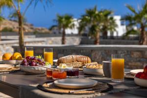 einen Tisch mit Essen, Orangensaft und Obst darauf in der Unterkunft Amani Villa Lindos Two in Lindos