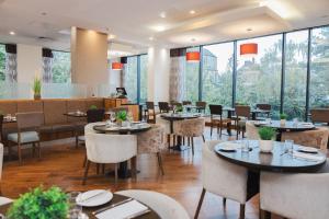 a restaurant with tables and chairs and large windows at Leonardo Hotel Derby in Derby