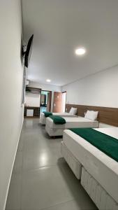um quarto com três camas com lençóis verdes em Gran Carlo Hotel em Taubaté