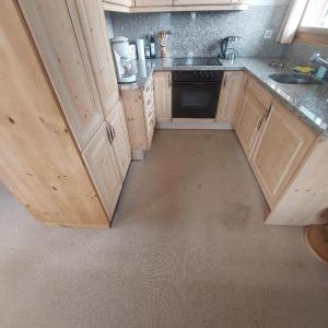 an empty kitchen with wooden cabinets and a sink at Ferienwohnung Caziela 49 in Tschappina +6 photos