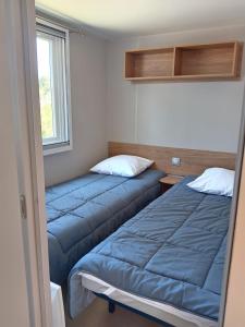 zwei blaue Betten in einem Zimmer mit Fenster in der Unterkunft MH 229 2 chambres et 1 salle de bain dans camping 4 étoiles avec parc aquatique in Saint-Julien-en-Born