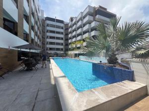 a swimming pool with a palm tree next to a building at Gold Flat Cabo Branco in João Pessoa