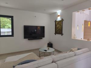 un salon blanc avec un canapé blanc et une télévision dans l'établissement l'Ecrin Vert Disney Land Maison 2chambres, à Chalifert