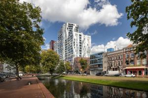 a tall white building next to a river with buildings at Westersingel in Rotterdam