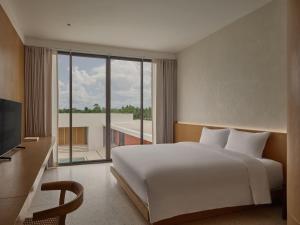 a bedroom with a white bed and a large window at Odina Hotel in Watthana Nakhon