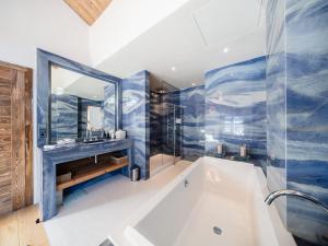 ein Badezimmer mit Badewanne, Waschbecken und Spiegel in der Unterkunft Chalet haut de gamme proche des pistes avec sauna et parking privé - FR-1-344-1209 in Saint-Martin-de-Belleville + 11 Fotos